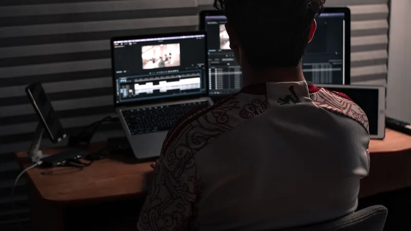 Person working at a dual-monitor desk setup, representing an AI-assisted video production workflow