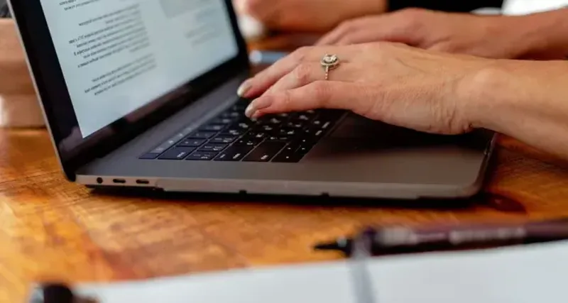 Hands typing on a laptop keyboard with a text document visible on screen