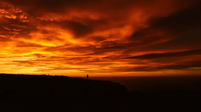 A silhouetted traveler facing a bright horizon, representing a faceless travel YouTube channel
