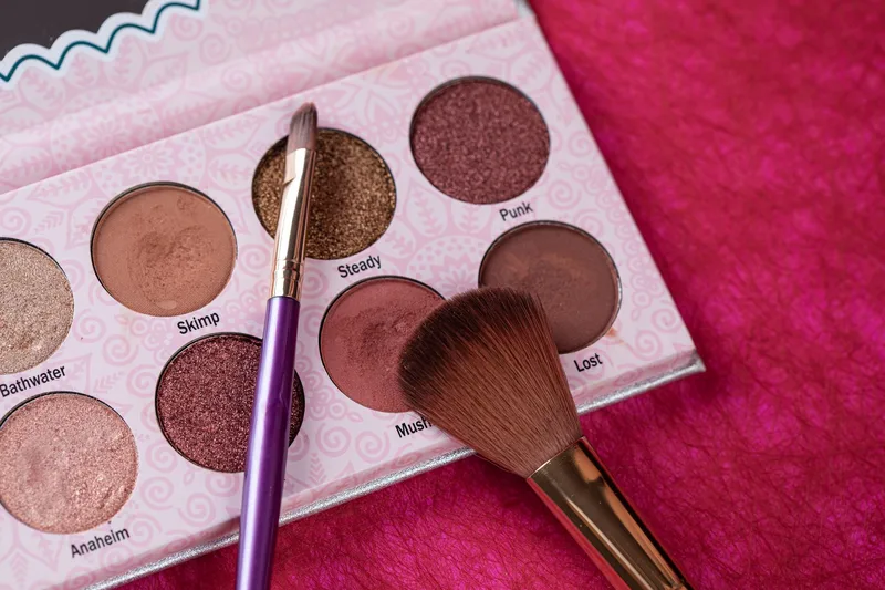 Colorful eyeshadow palette with makeup brushes arranged on a textured background