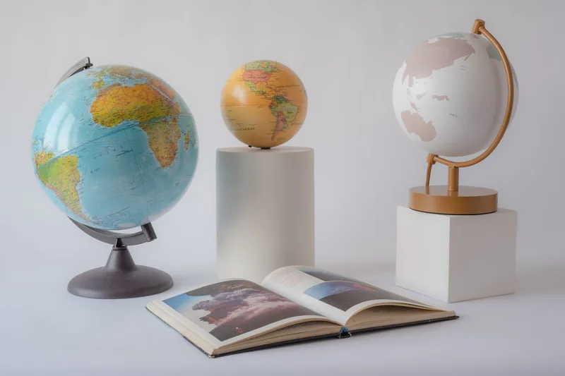 Three globes and an open book on display representing world knowledge, education, and fun facts content formats