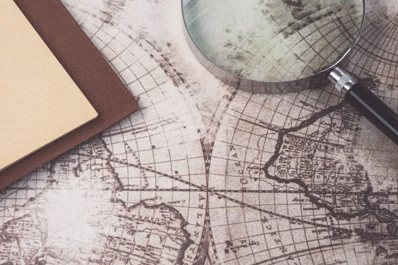 A vintage map, magnifying glass, and notebook representing geographic research and world exploration for niche discovery