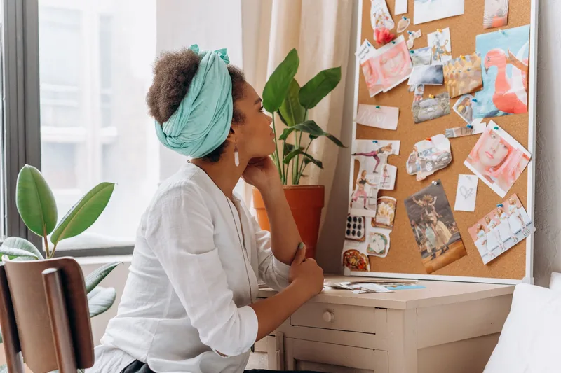A vision board of cutout images and goals pinned to a corkboard