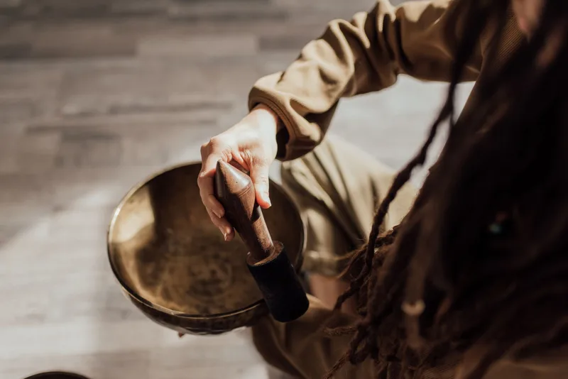 Close-up of a person using a singing bowl, demonstrating meditation sound therapy