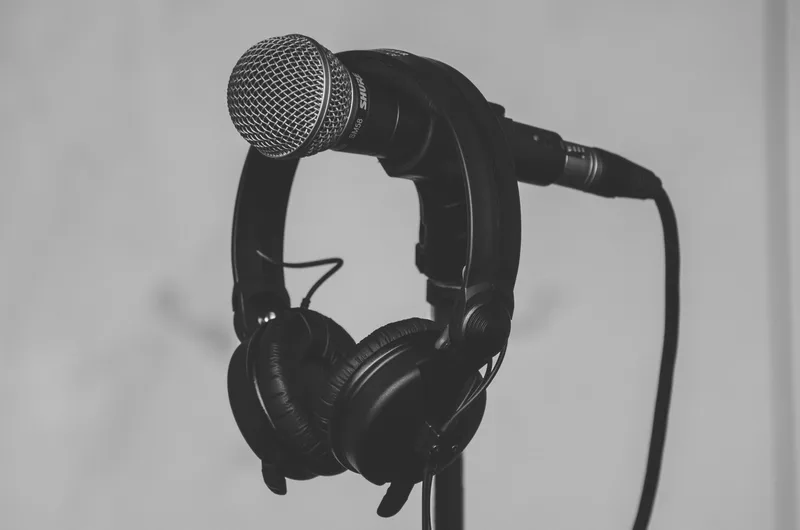Black and white close-up of a microphone and headphones on a stand