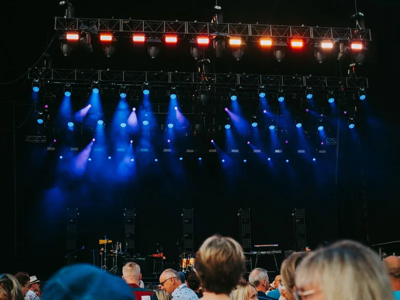 Night concert scene with audience, colorful stage lighting, no visible individual faces