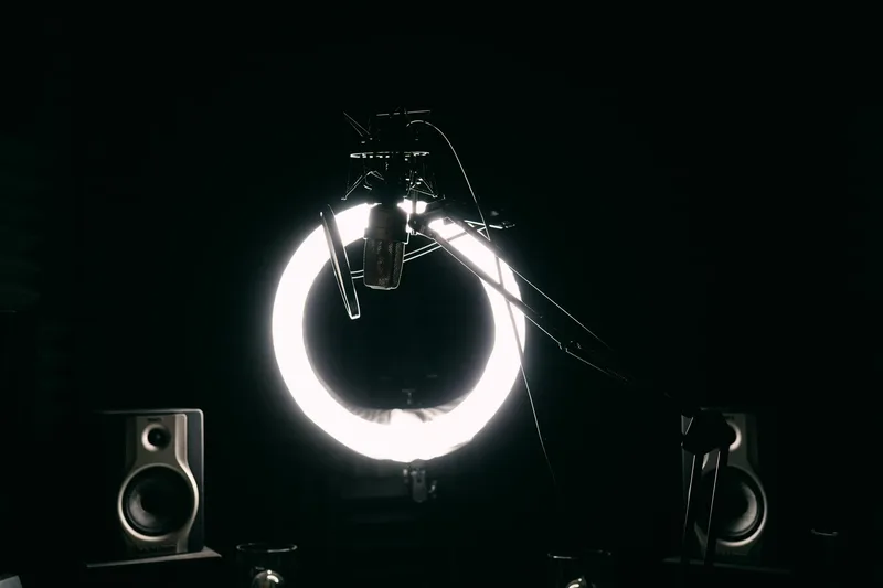 A condenser microphone and ring light in a dark recording setup