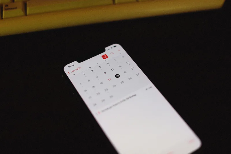 Smartphone displaying a calendar app on a dark background, no person visible