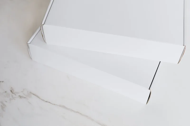 Two closed white shipping boxes on a marble tabletop, ready to send
