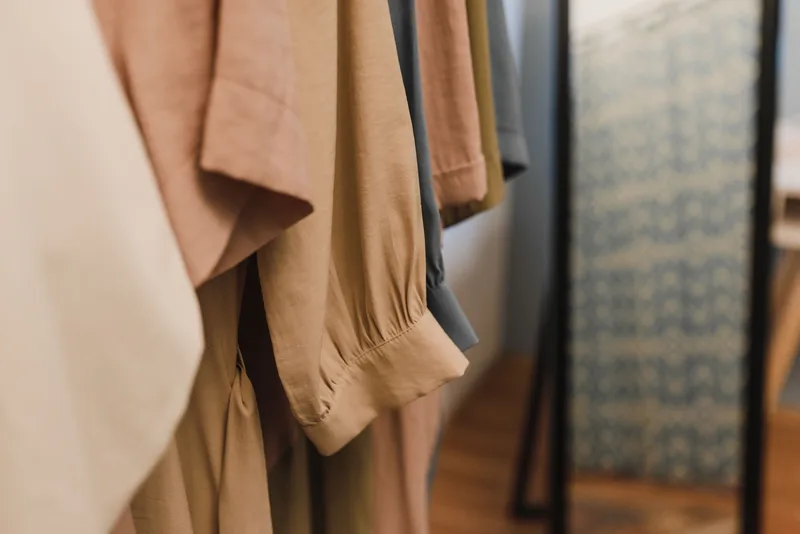 Close-up of beige and tan clothes hanging in a wardrobe