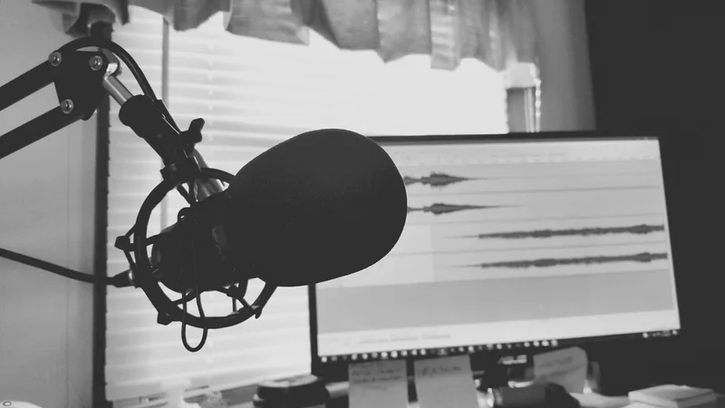 Black and white podcast microphone with audio waveform visible representing voiceover recording setup