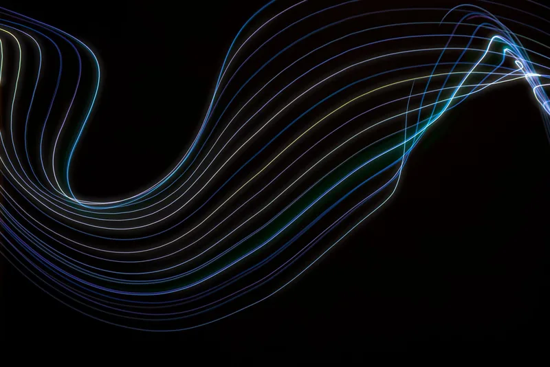 Abstract flowing light-wave patterns on a black background representing AI-generated motion