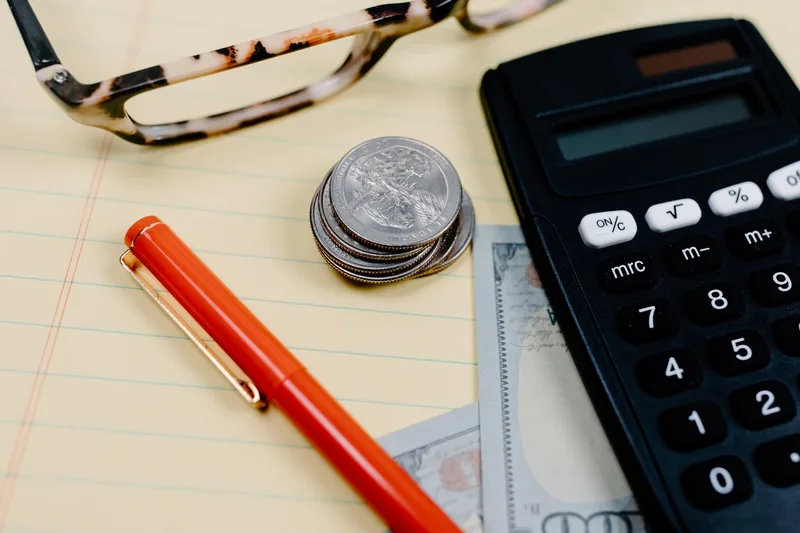 Calculator, coins, and cash on a desk representing subscription cost comparison