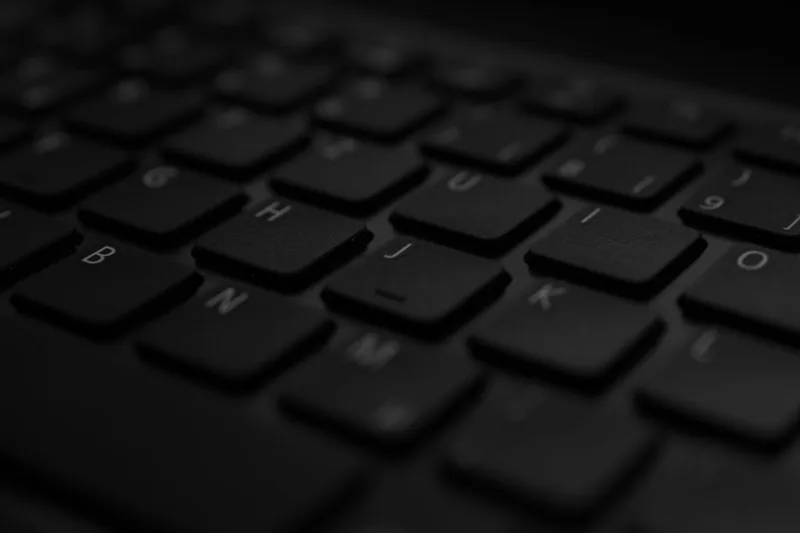 Close-up of a dark laptop keyboard lit from an angle