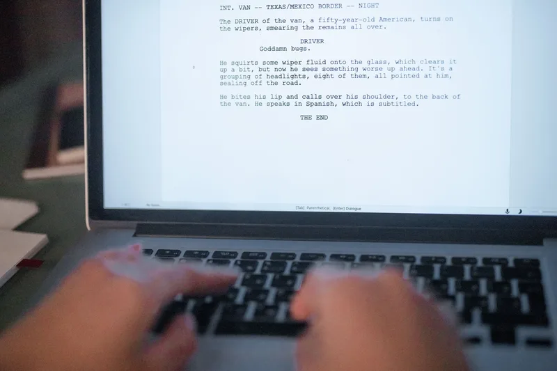 Close-up of hands writing a script on a laptop for AI video production
