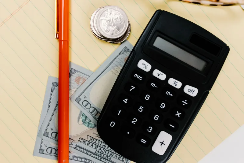 Close-up of a calculator, pen, and cash, representing subscription cost comparison