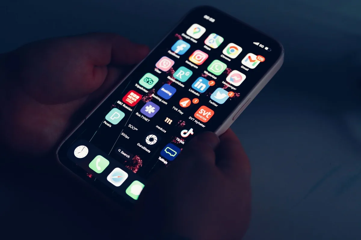 Close-up of hands holding a smartphone scrolling a vertical video feed in a dimly lit room