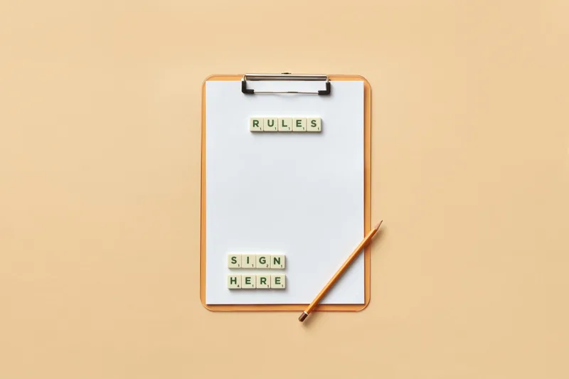 Flat lay of a clipboard with letter tiles and a pencil on a beige background