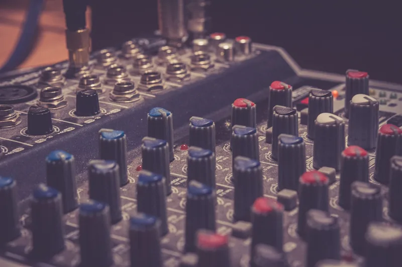 Detailed view of a professional audio mixer with control knobs and switches in a music studio