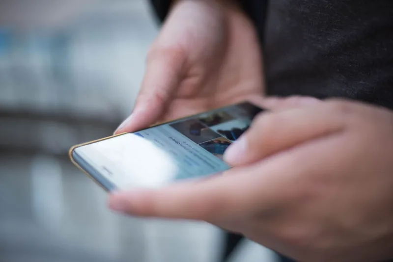 Close-up of two hands scrolling a feed on a smartphone