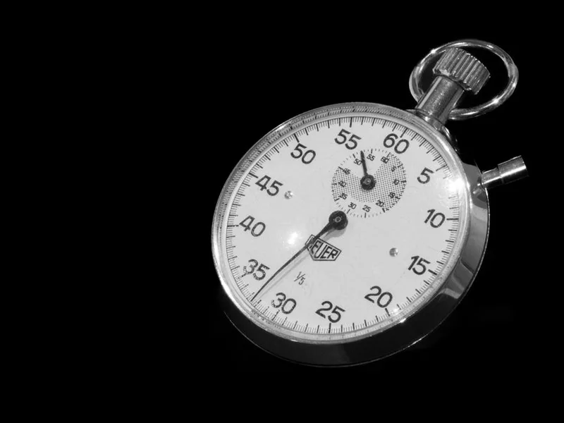 Vintage mechanical stopwatch on a dark background, representing script timing, no person visible