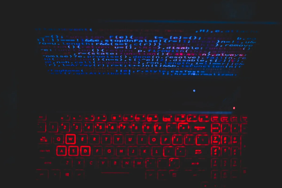 Dark laptop setup with a red glowing keyboard and code on screen