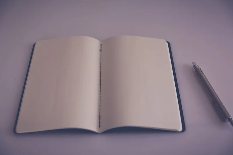 Open notebook with blank pages and a pen on a desk